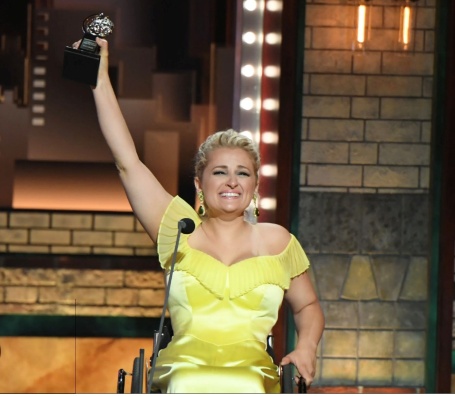 A person in a wheelchair holding a trophyAI-generated content may be incorrect.